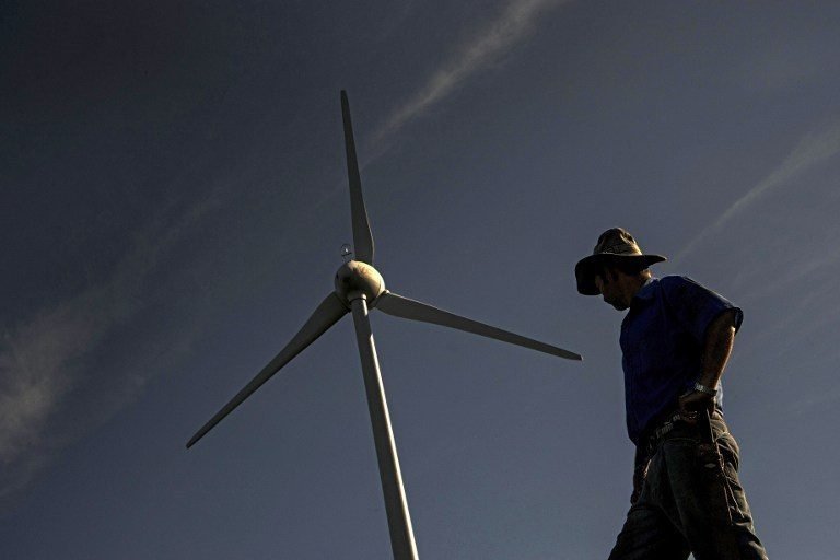 A farmer stands near a wind mill of the National Power and Light Company in Santa Ana, Costa Rica on October 23, 2015. Costa Rica expects to conclude in 2015 an energy matrix made in a 97.1% of renewable sources, what would make the Central American country one of the cleanest in the world, aiming at reducing carbon emissions to curb global warming. AFP PHOTO / Ezequiel BECERRA