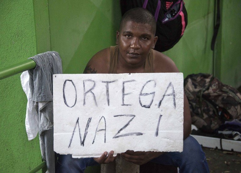 A Cuban man holds a sign referring to Nicaraguan President Daniel Ortega in Penas Blancas, Guanacaste, Costa Rica, in the border with Nicaragua on November 16, 2015. A surge of some 2,000 Cuban migrants trying to cross Central America to reach the United States triggered a diplomatic spat between Costa Rica and Nicaragua Monday, plunging tense relations between the two countries to a new low. AFP PHOTO / Ezequiel BECERRA