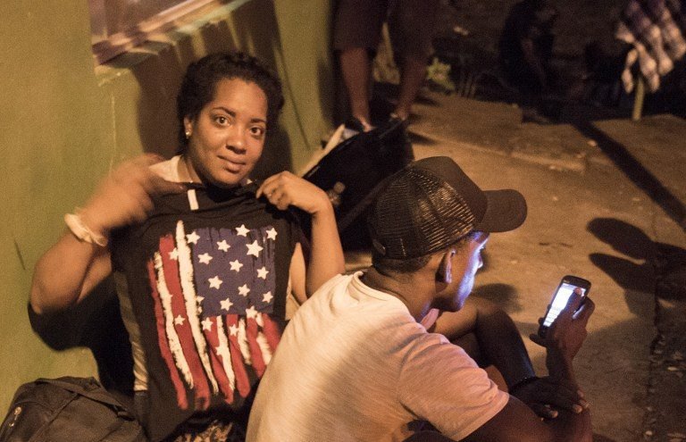 An unidentified Cuban woman displays an American flag in Penas Blancas, Guanacaste, Costa Rica, on the border with Nicaragua on November 16, 2015. A surge of some 2,000 Cuban migrants trying to cross Central America to reach the United States triggered a diplomatic spat between Costa Rica and Nicaragua, plunging tense relations between the two countries to a new low. AFP PHOTO / Ezequiel BECERRA