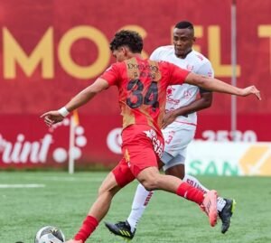 Jugador del Herediano, Andy Rojas, controlando el balón en un partido de fútbol mientras es marcado por un defensor del equipo rival